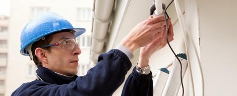 Technician installs a security camera system on the exterior of a commercial building